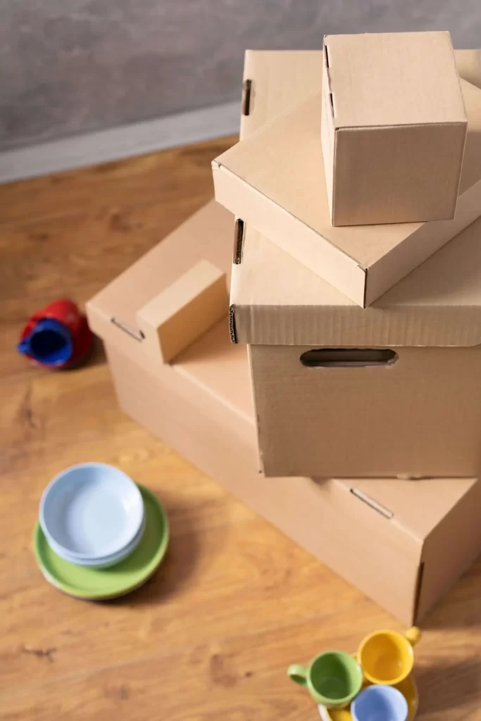 Fotografía de una pila de cajas de cartón y herramientas de embalaje como cinta adhesiva y film protector.